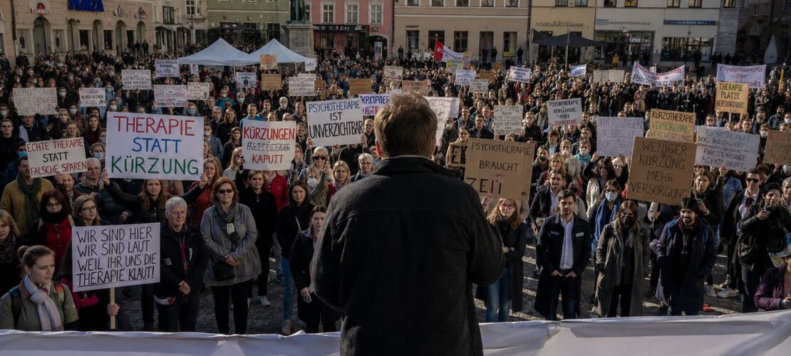 Menschen demonstrieren mit Schildern auf einem Platz
