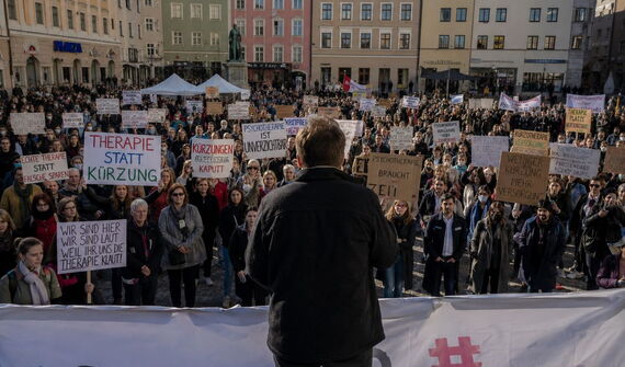 Menschen demonstrieren mit Schildern auf einem Platz
